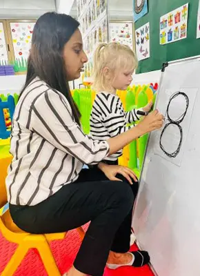 Teacher supporting a child during a guided classroom learning activity in Dubai